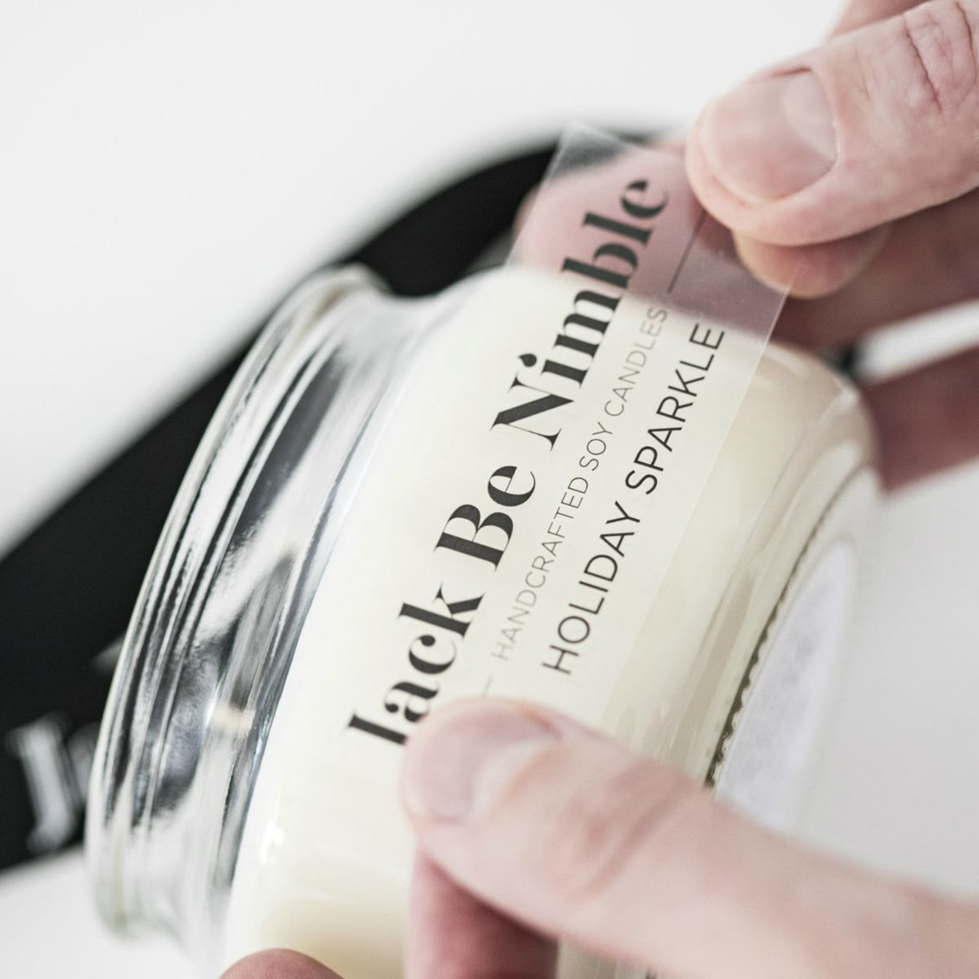 Clear transparent label on glass candle jar with minimalist logo.